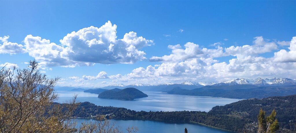 Lago Nahuel Huapi com ilhas e montanhas ao fundo, visto do alto de um morro