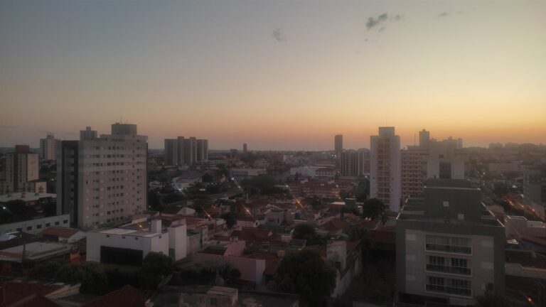 Vista de Bauru com os edifícios da cidade e céu alaranjado